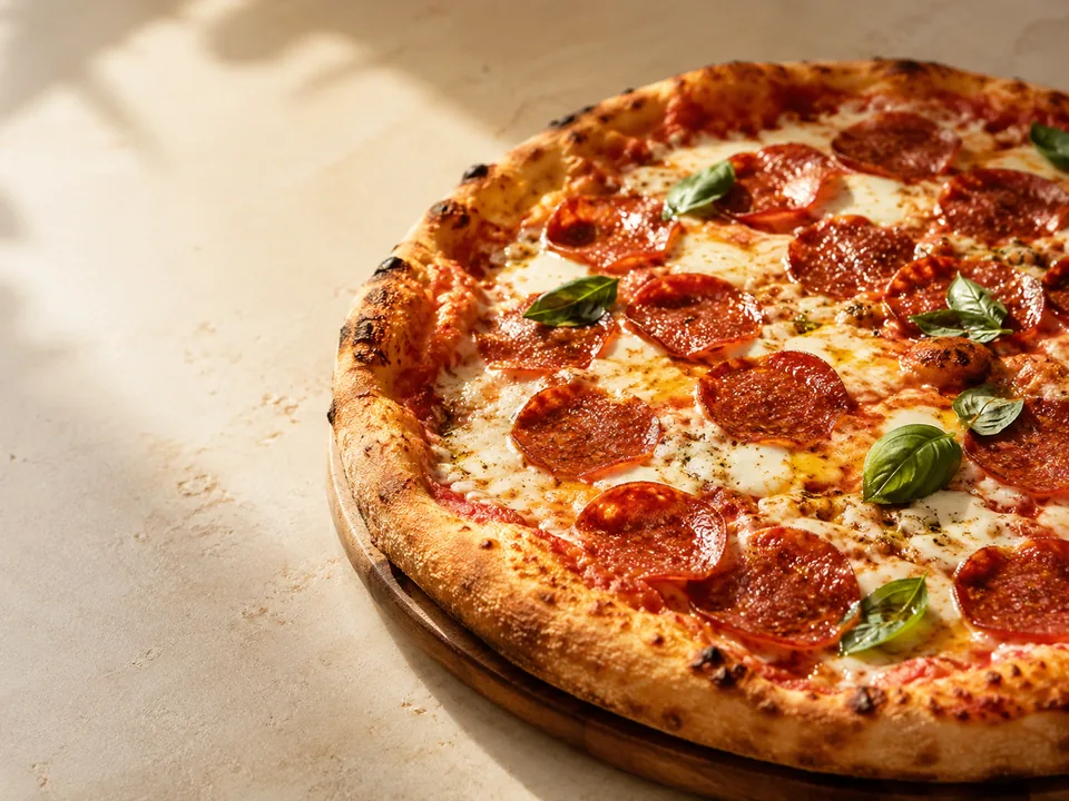 Frisch gebackene Pizza mit Salami, Käse und Basilikum